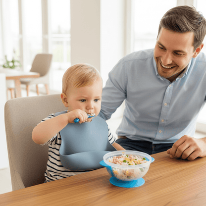 Un enfant prend son repas dans son assiette bébé ventouse bleue en autonomie à côté de son père