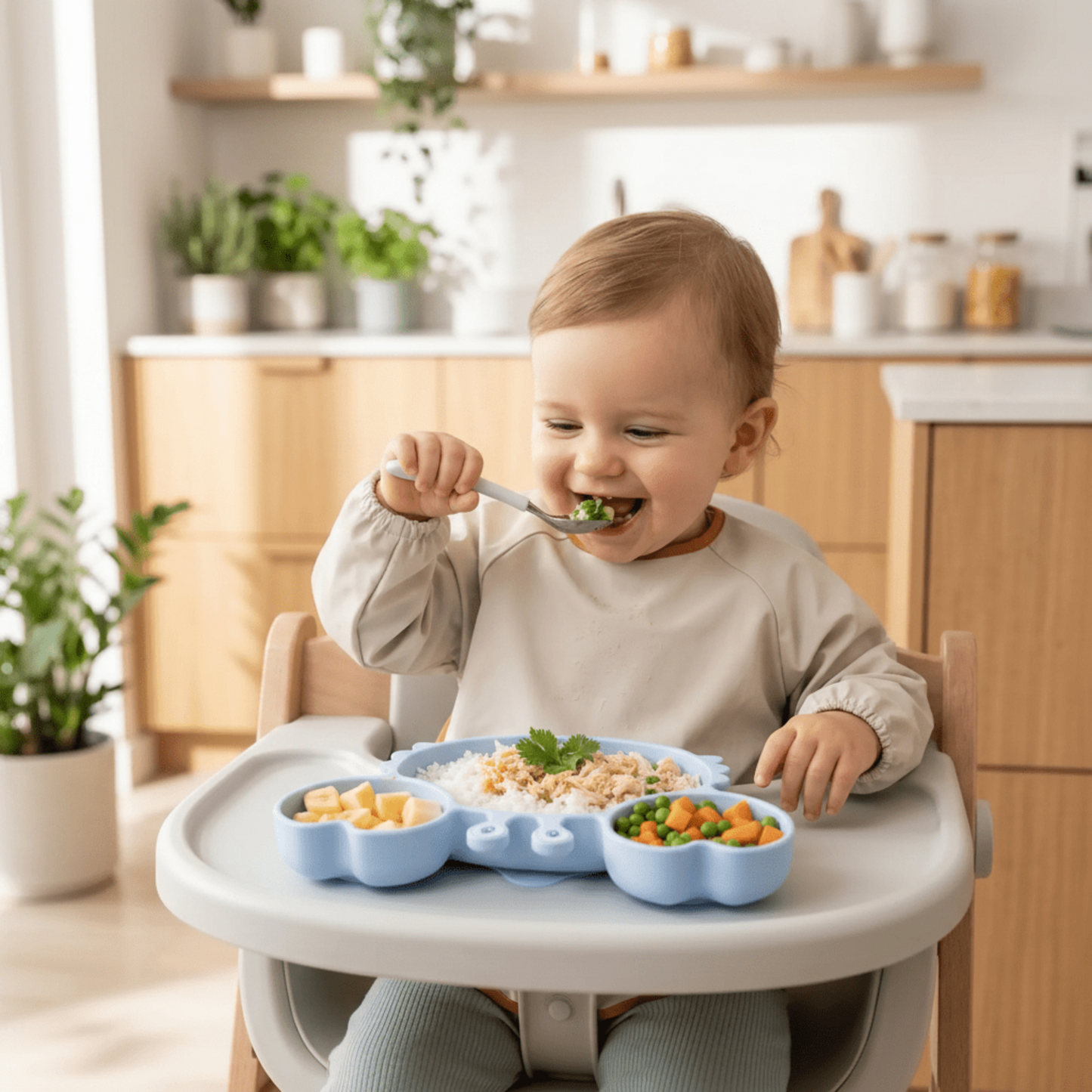 enfant heureux devant son assiette compartiment bébé bleue en forme de crabe ventousée sur sa tablette de chaise haute 