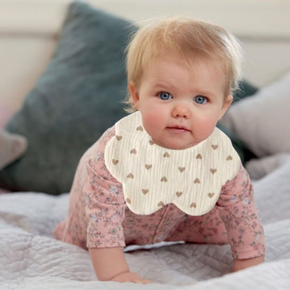 fillette en quatre pattes portant le bavoir bebe forme fleur et motif coeurs