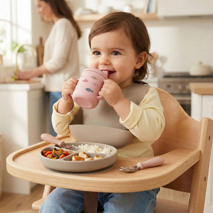 une fillette prend son déjeuner avec son bavoir bébé avec poche imperméable coloris taupe