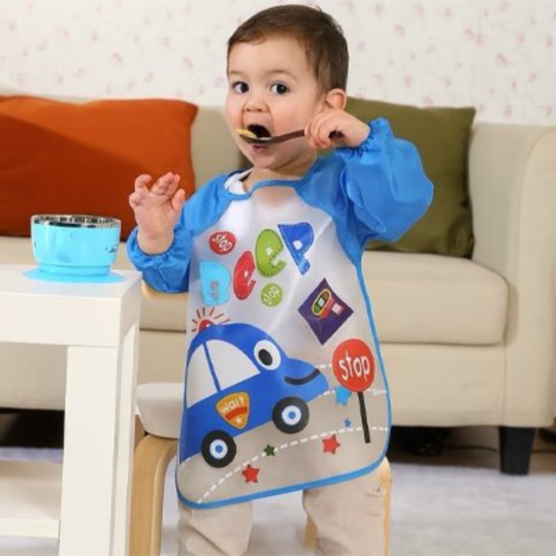 Bavoir bébé manche longue etanche bleu motif voiture porté par un enfant  qui mange debout