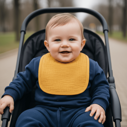 un bébé en promenade dans sa poussette porte le bavoir en coton absorbant jaune moutarde