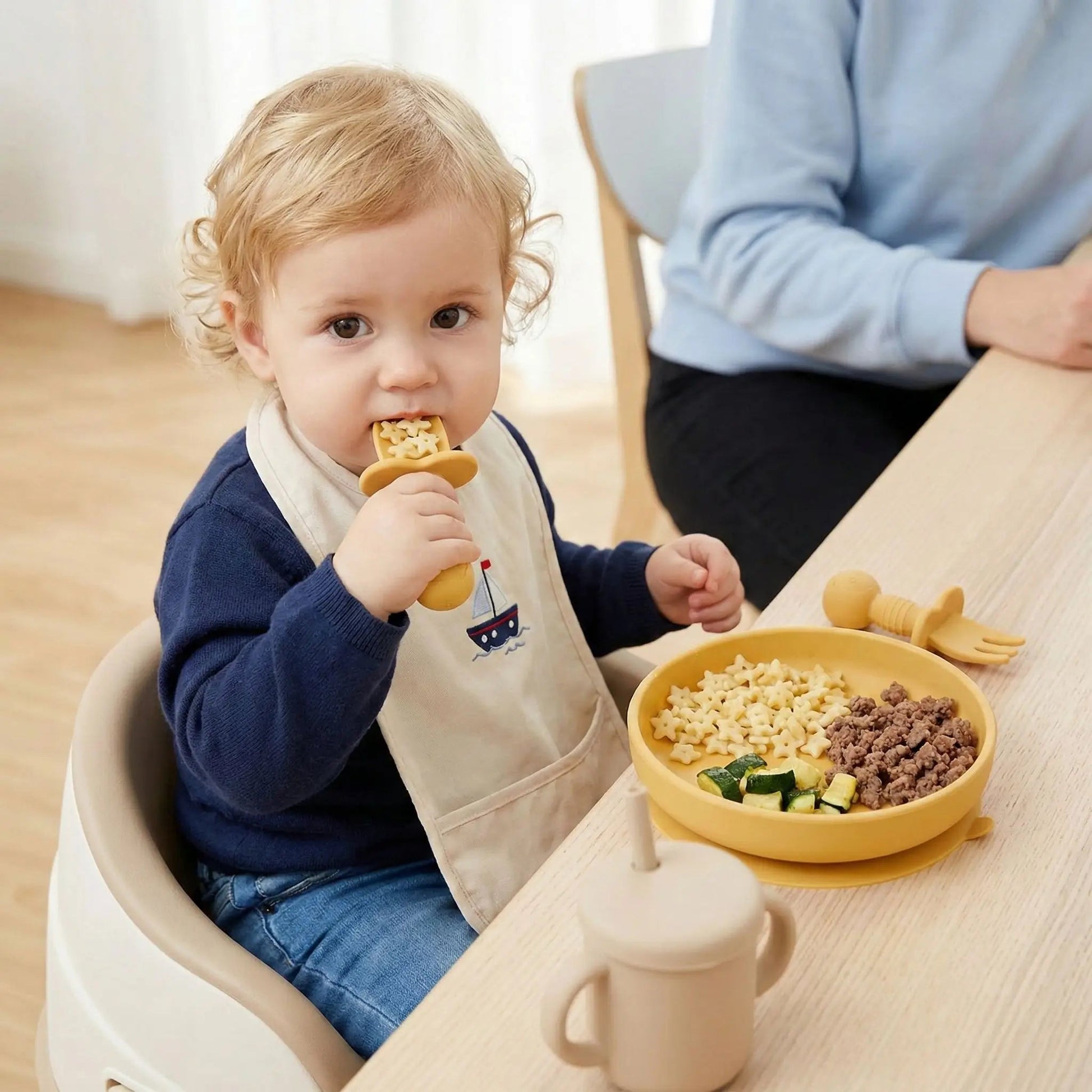 un enfant mange son repas comme un grand avec son couvert bébé ergonomique jaune