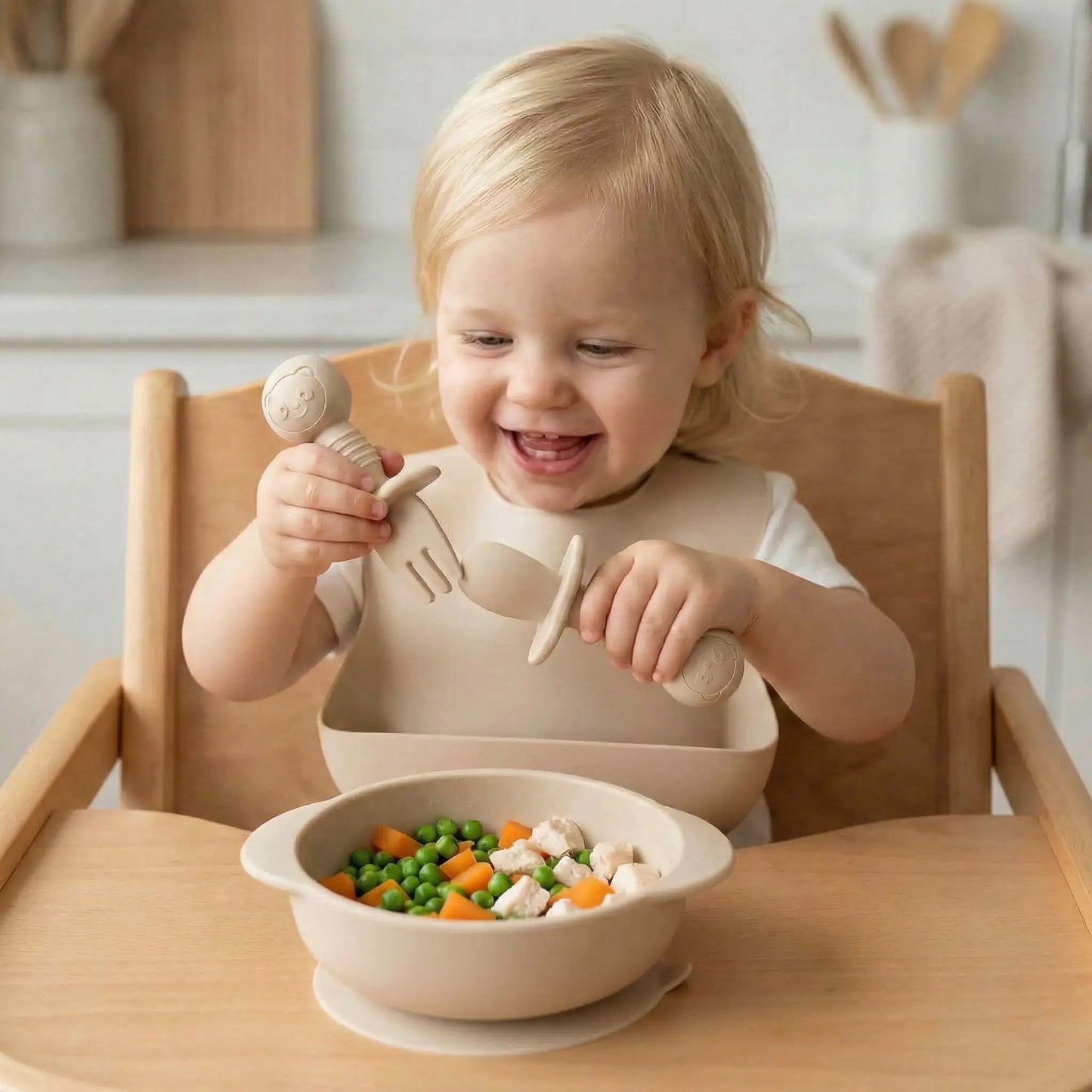 un enfant joue avec son couvert bébé ergonomique beige : c'est plus amusant que les petits pois carotte ! 