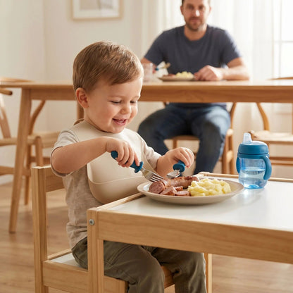 un enfant autonome déjeune à sa petite table de salle à manger avec son couvert pour bebe coloris bleu