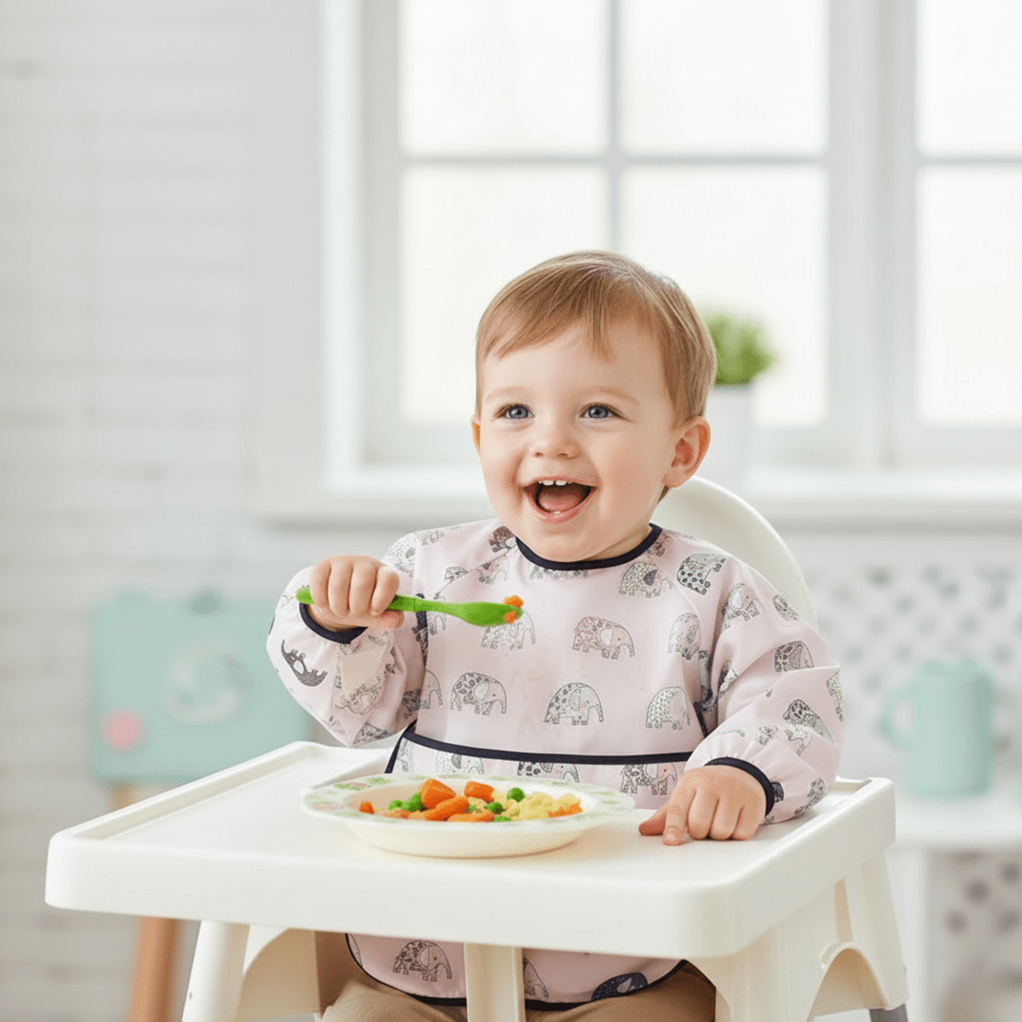 un enfant portant le bavoir bébé manche longue modèle éléphant mange tout seul ses légumes avec sa cuillère