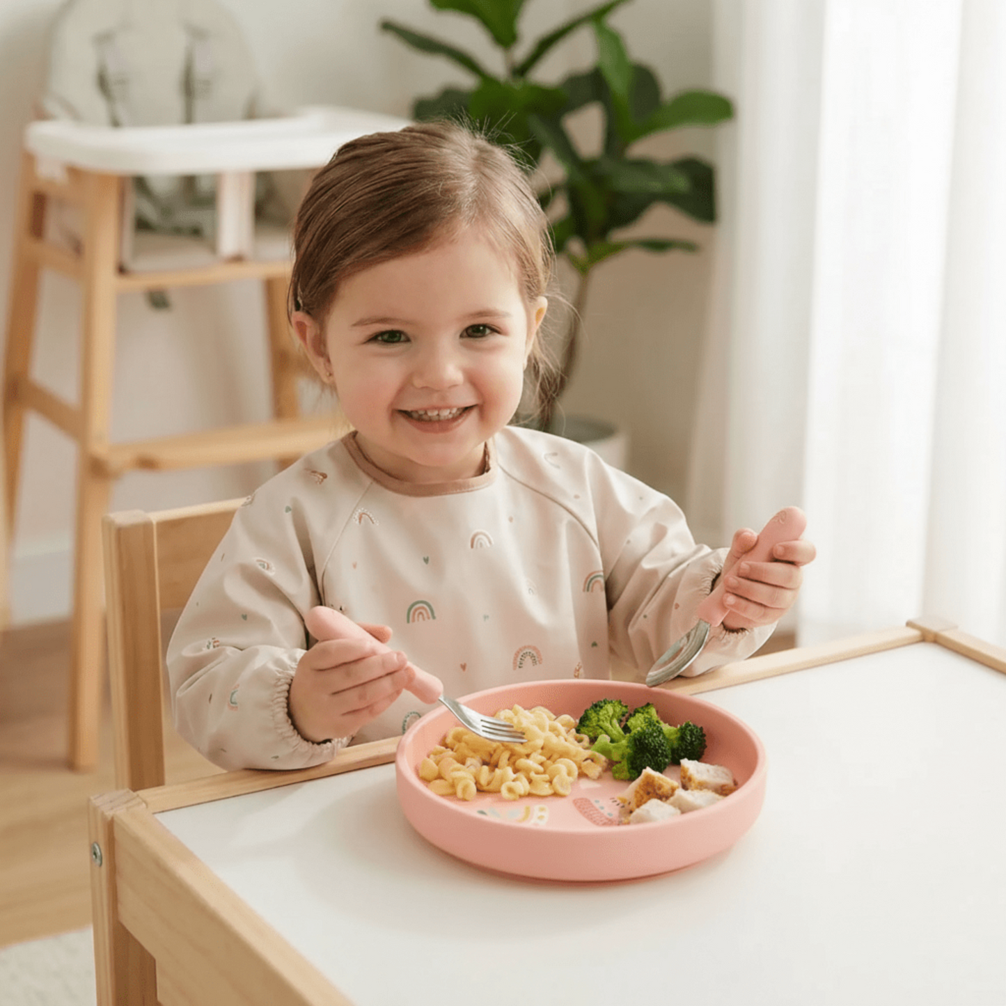 fillette à table avec son assiette bebe en silicone coloris rose motif coeur rainbow