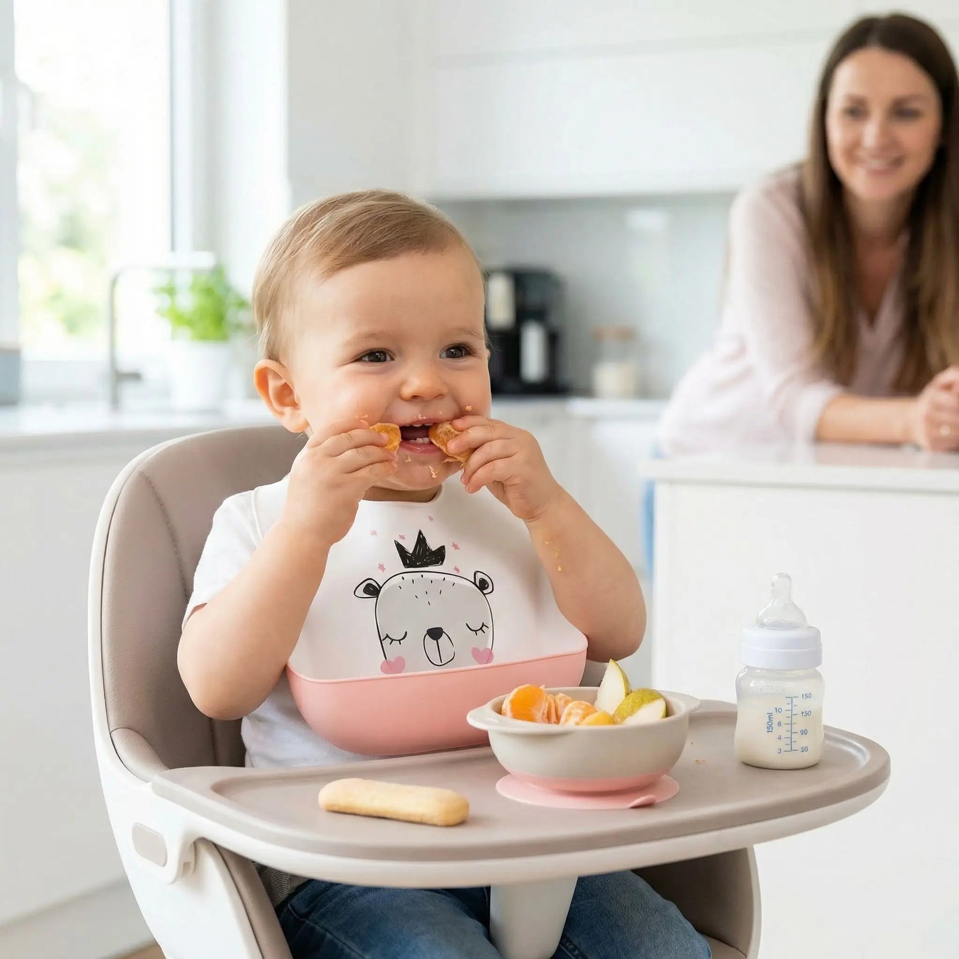 un petit garçon picore des fruits en portant son bavoir impermeable en silicone blanc motif ours