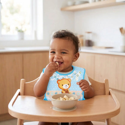 goûter de banane en portant le bavoir bebe impermeable avec poche amovible coloris bleu motif ourson