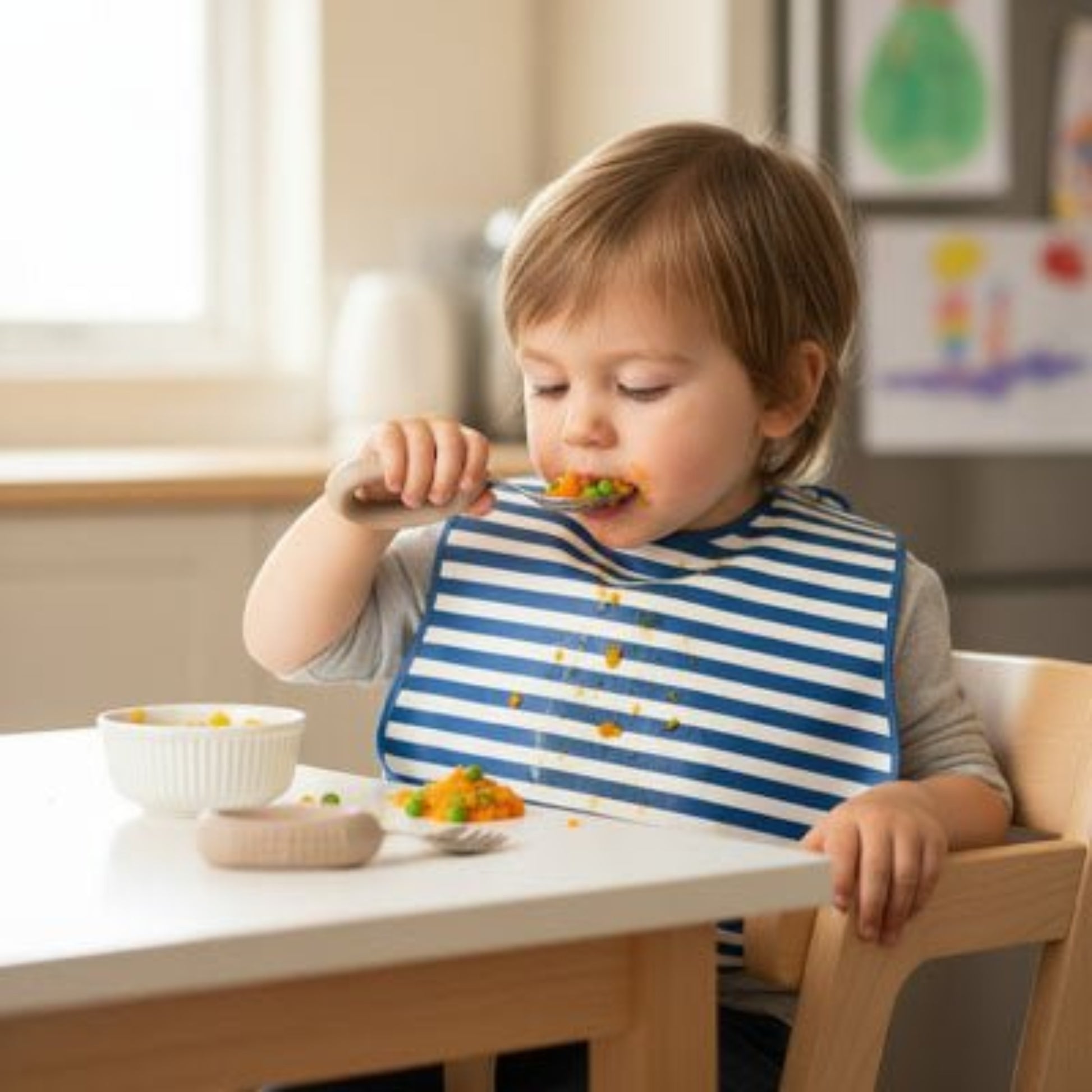 un enfant prend une grosse bouchée de légumes avec son couvert bebe avec poignee grip coloris marron