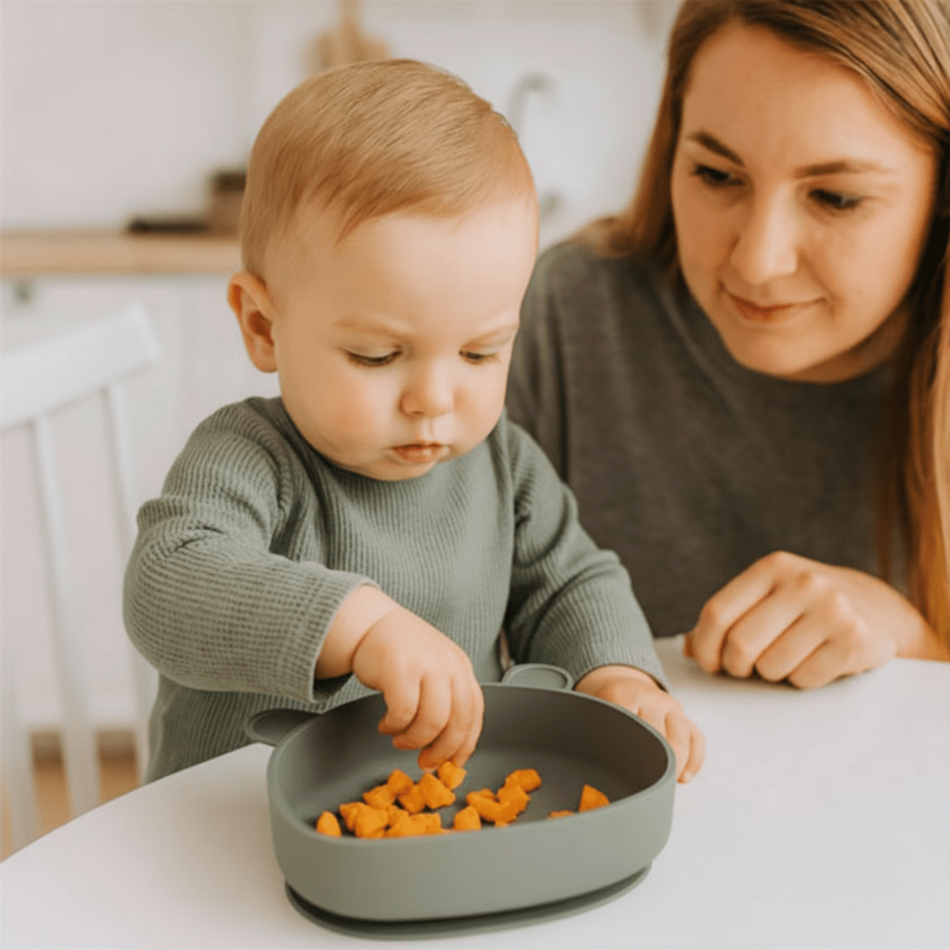 une maman regarde son enfant picorer dans son assiette bébé ventouse coloris vert