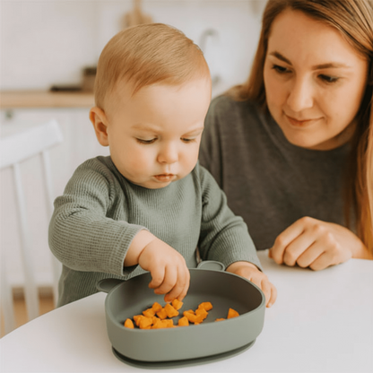 une maman regarde son enfant picorer dans son assiette bébé ventouse coloris vert