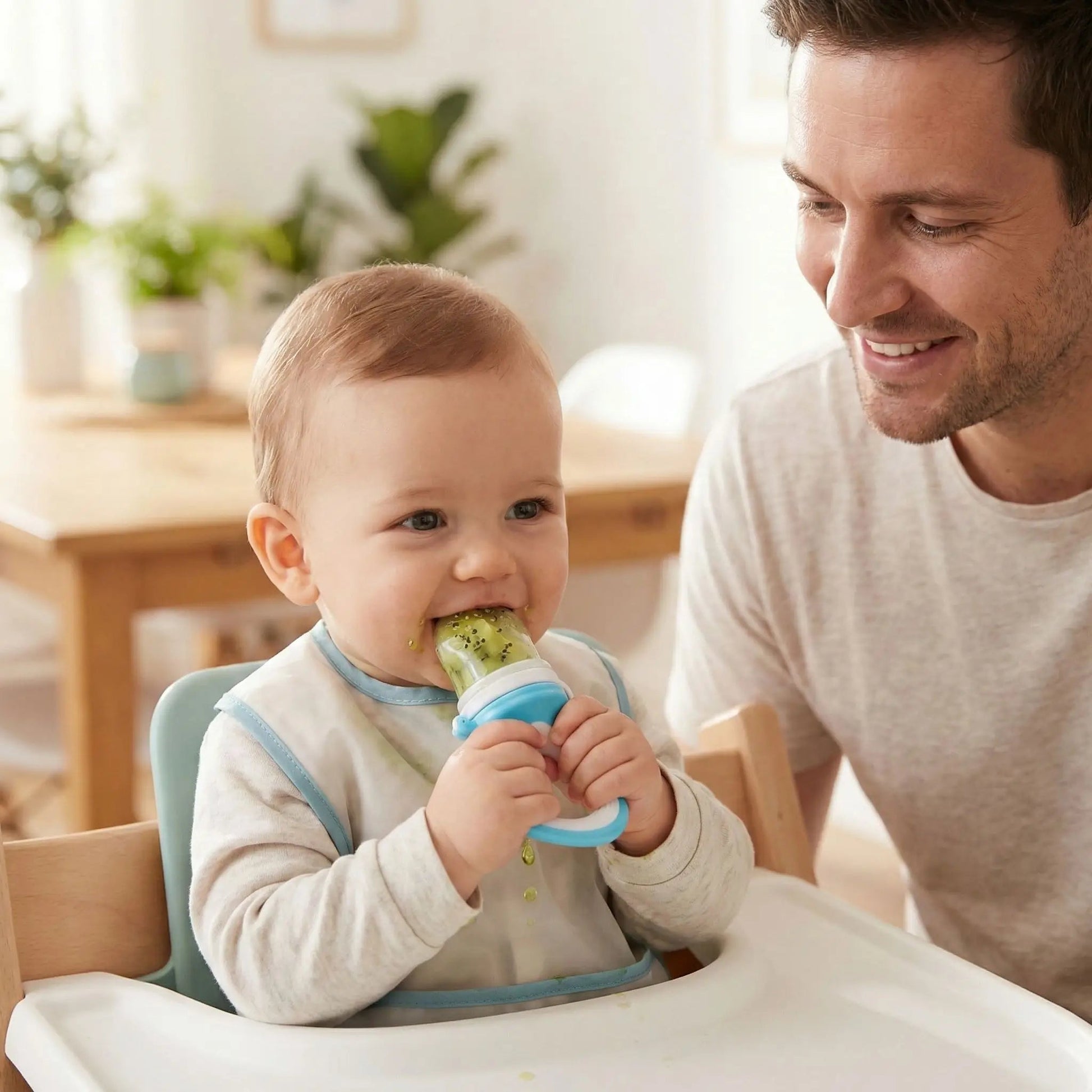 un papa donne à son bébé pour le goûter des fruits dans la grignoteuse bébé securdent coloris bleu