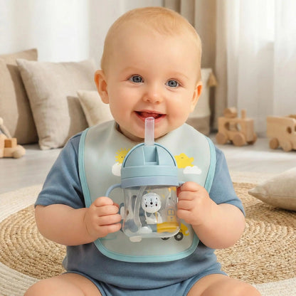 un petit garçon assis sur un tapis tient son verre bébé avec paille bleu anti-fuite en souriant