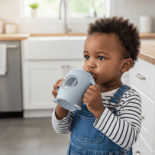 enfant debout tenant les anses de la tasse d'apprentissage bebe avec hublot coloris bleu